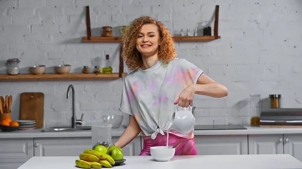 Jovens Felizes Derramando Flocos Milho Tigela Perto Frutas Mesa Cozinha — Fotografia de Stock