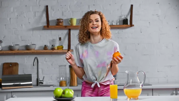 Cheerful Woman Holding Orange Apples Kitchen Table — Stock Photo, Image