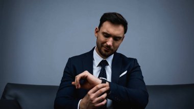 Resmi işadamı otel odasında kol saatine bakıyor. 