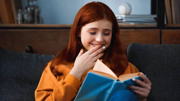 Positive Teenager Hand Mouth Reading Book Blurred Foreground — Stock Photo, Image