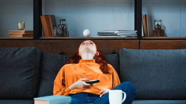 Ragazza Che Tiene Telecomando Vicino Tazza Libro Primo Piano Sfocato — Foto Stock