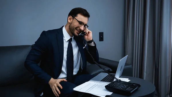 Glimlachende Zakenman Aan Telefoon Buurt Van Kranten Laptop Het Hotel — Stockfoto