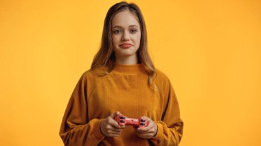 KYIV, UKRAINE - 24 Şubat 2021: Sarı alanda video oyunu oynayan gülümseyen genç kız