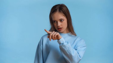 Eşofmanlı genç kız mavi üzerine parmak işareti yapıyor.