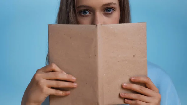 Teenage Girl Looking Camera While Covering Face Book Isolated Blue — Stock Photo, Image