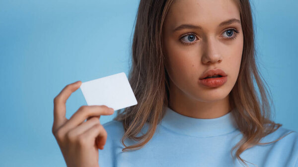 Девочка-подросток в толстовке с пустой карточкой, изолированной на голубом