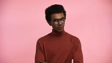 african american teenager in turtleneck sweater and glasses isolated on pink clipart