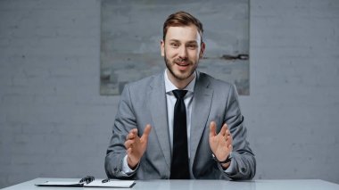 businessman in suit talking while gesturing during interview in office
