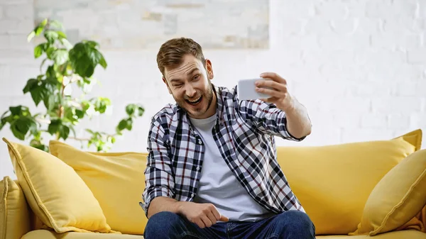 Animado Homem Tomando Selfie Celular Enquanto Piscar Olhos Sala Estar — Fotografia de Stock