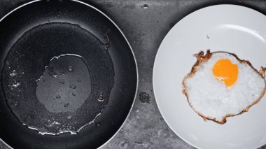 top view of fried egg on white plate near frying pan 
