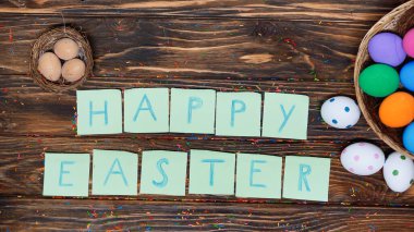 top view of papers with happy easter lettering near painted eggs 