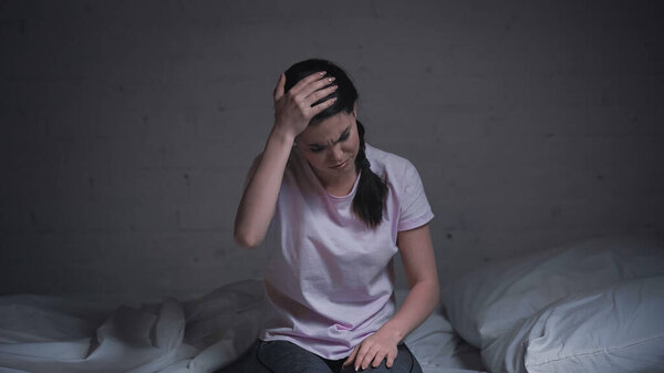 brunette young woman suffering from headache at night