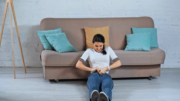 Mladá Žena Sedí Zapínání Džíny Obývacím Pokoji — Stock fotografie