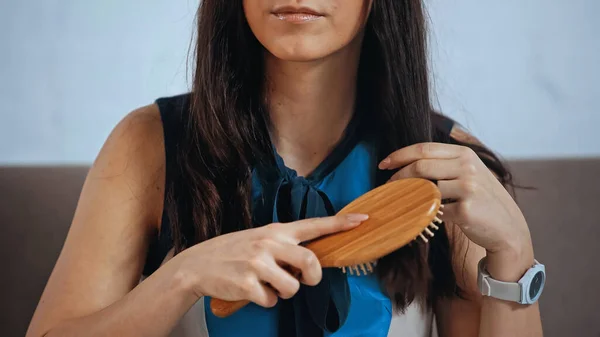 cropped view of upset woman brushing hair