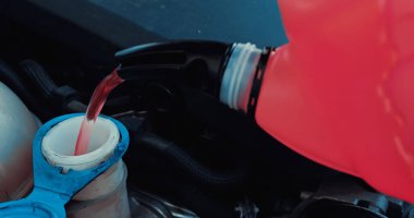 Motor yağı teneke kutudan arabanın motoruna akıyor.