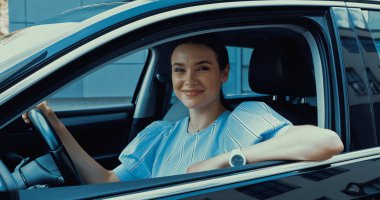 Modern siyah araba süren neşeli genç bir kadın.