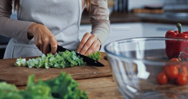 cropped view of woman cutting green lettuce on chopping board clipart