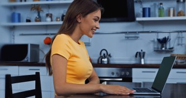 Mutlu genç serbest çalışan boş ekranlı dizüstü bilgisayara bakıyor.