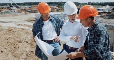 engineer and builders discussing blueprint on construction site clipart