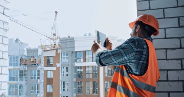 Builder taking photo with digital tablet on construction site clipart