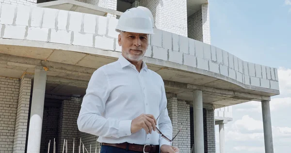 Mature Engineer Holding Eyeglasses Construction Site — Stock Photo, Image