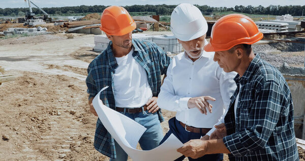 engineer and builders discussing blueprint on construction site