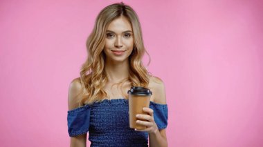 Sarışın kadın elinde kahve bardağıyla pembeleşmek için kağıt bardak tutuyor.
