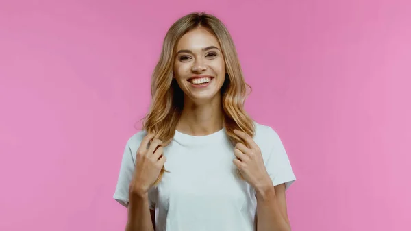 Jovem Feliz Tocando Cabelo Sorrindo Isolado Rosa — Fotografia de Stock