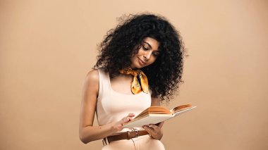 Young hispanic woman reading book isolated on beige  clipart
