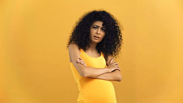 Оскорбленная беременная латиноамериканка смотрит в камеру, изолированную на желтый