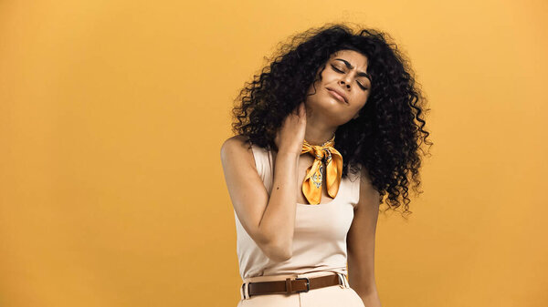 латиноамериканка, страдающая от боли в шее, изолированной на желтом