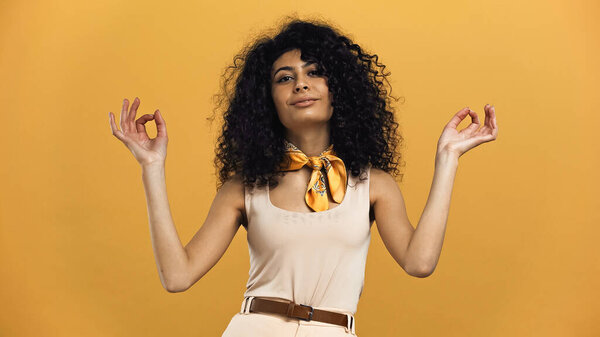 Улыбающаяся латиноамериканка демонстрирует нормальный жест, изолированный на жёлтом