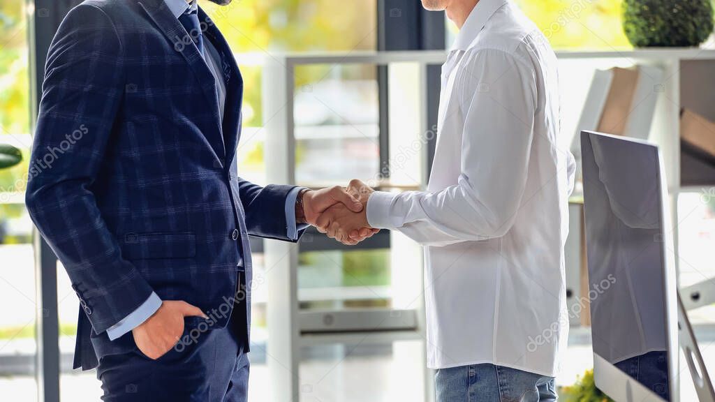 cropped view of businessmen shaking hands in office