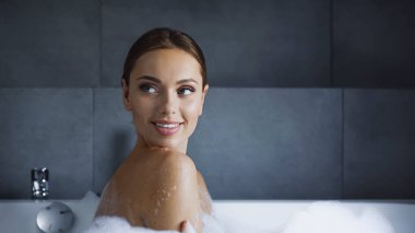 Neşeli genç bir kadın evde banyo yaparken gözlerini kaçırıyor.
