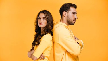 offended boyfriend and girlfriend standing back to back isolated on yellow clipart