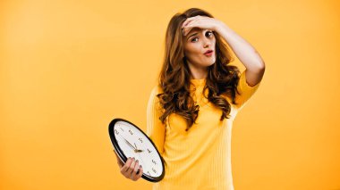 curly woman holding clock isolated on yellow clipart