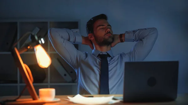Κουρασμένος Επιχειρηματίας Τεντώνεται Ενώ Εργάζεται Μέχρι Αργά — Φωτογραφία Αρχείου