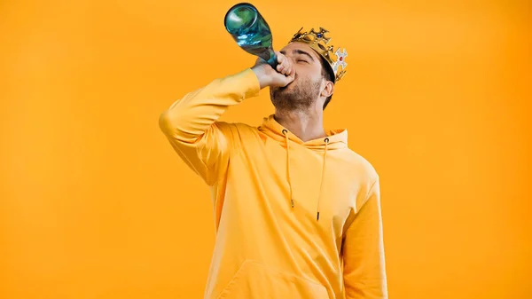 Άνθρωπος Στο Στέμμα Πίνοντας Σαμπάνια Από Μπουκάλι Απομονωμένο Κίτρινο — Φωτογραφία Αρχείου