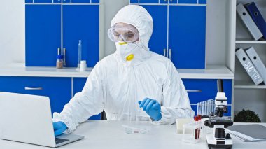 virologist in hazmat suit working on laptop in laboratory clipart