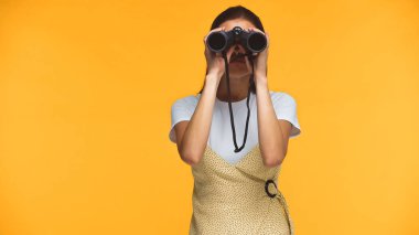 woman looking through binoculars isolated on yellow clipart