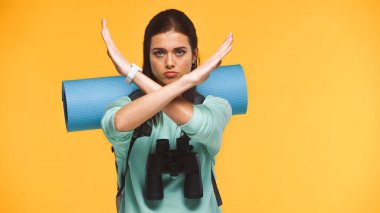Sırt çantalı gezgin, spor minderli ve dürbünlü dur işaretini sarı renkte gösteren.