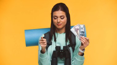 Sırt çantalı gezgin yanan çakmağı sarıda izole edilmiş paranın yanında tutuyor.