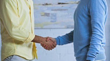 cropped view of businessmen shaking hands in office clipart