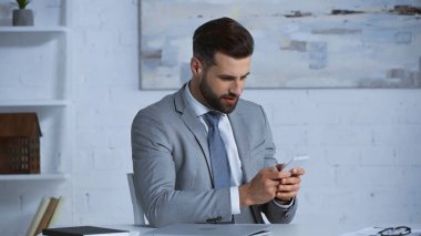 İş yerindeki resmi işadamı, iş yerinde cep telefonuyla sohbet ederken giyiniyor