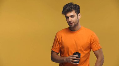 Sakallı adam sarı bardakta duruyor.