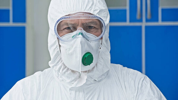 scientist in hazmat suit looking at camera in laboratory