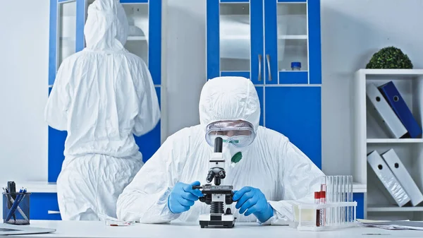 Cientista Terno Hazmat Trabalhando Com Microscópio Perto Colega Laboratório — Fotografia de Stock