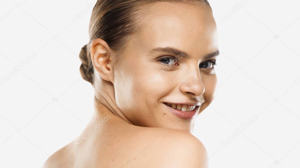 smiling young woman with bare shoulders looking at mirror isolated on white