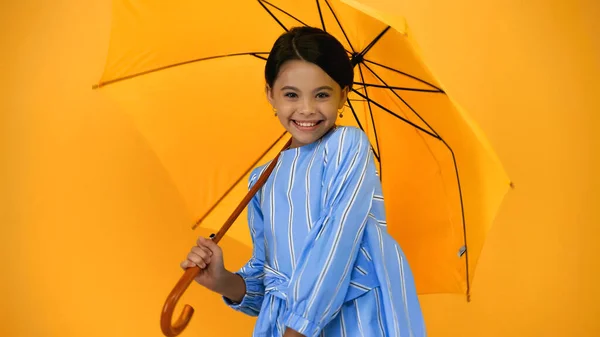 Vidám Gyermek Kék Ruhában Áll Esernyő Alatt Elszigetelt Sárga — Stock Fotó
