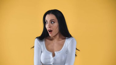 shocked young woman with open mouth looking away isolated on yellow clipart
